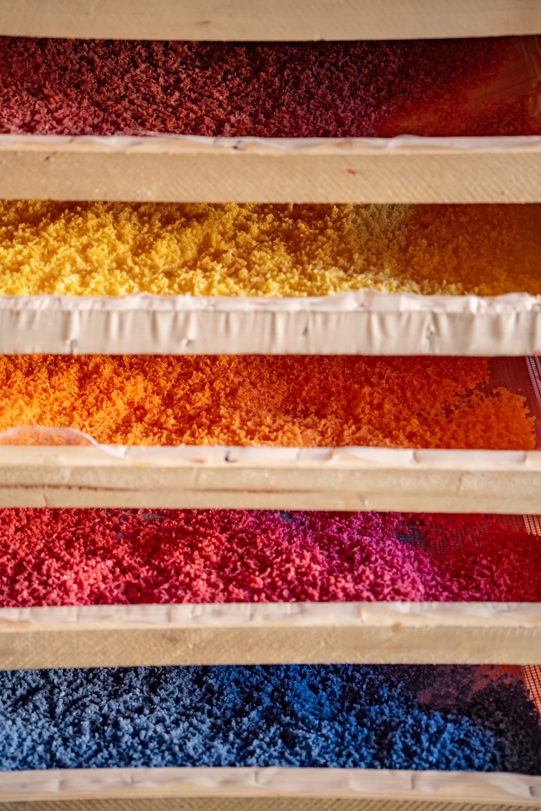 Eingefärbte Wachs-Späne aus gespendeten Kerzenresten in Trockengestellen der Werkstatt